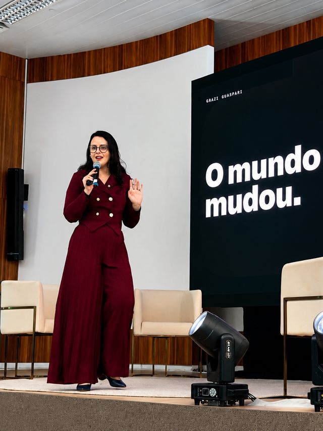 Grazi Guaspari no palco, diante do telão com a frase O mundo mudou